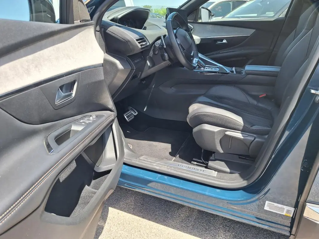 Vue côté conducteur intérieur du Peugeot 3008 Hybrid 225 e-EAT8 GT Pack bleu clair, avec siège en cuir et tableau de bord moderne.