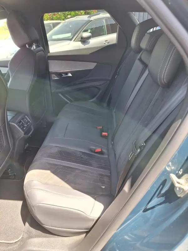 Vue intérieure côté droit des sièges arrière en cuir noir du Peugeot 3008 Hybrid 225 e-EAT8 GT Pack bleu clair, avec ceinture et appuie-tête.