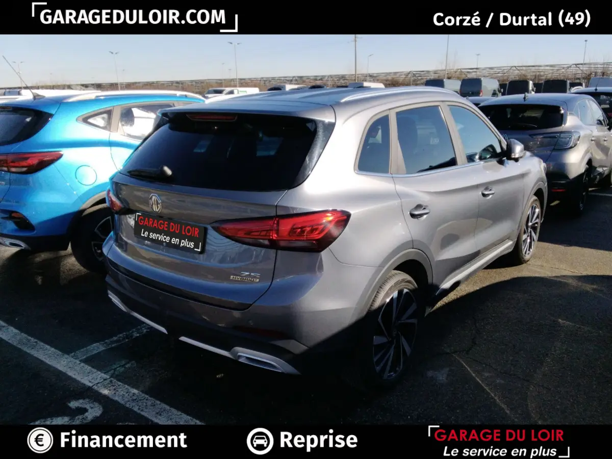 Vue 3/4 arrière droite d'un MG ZS gris clair hybride avec feux arrière LED et jantes alliage noires.