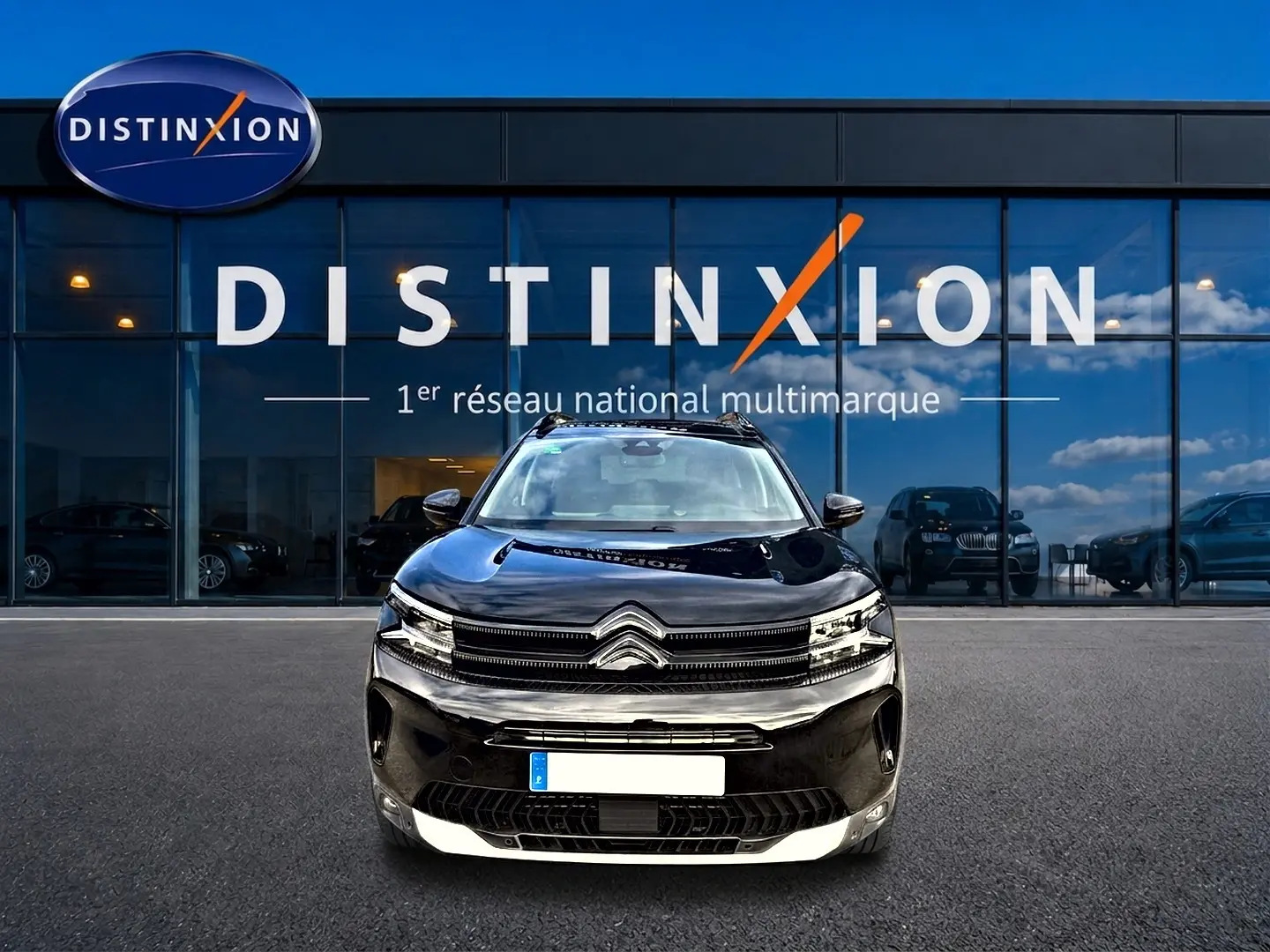 Vue avant d'un Citroën C5 Aircross noir 2025, avec calandre distinctive et phares LED, devant un showroom Distinxion.