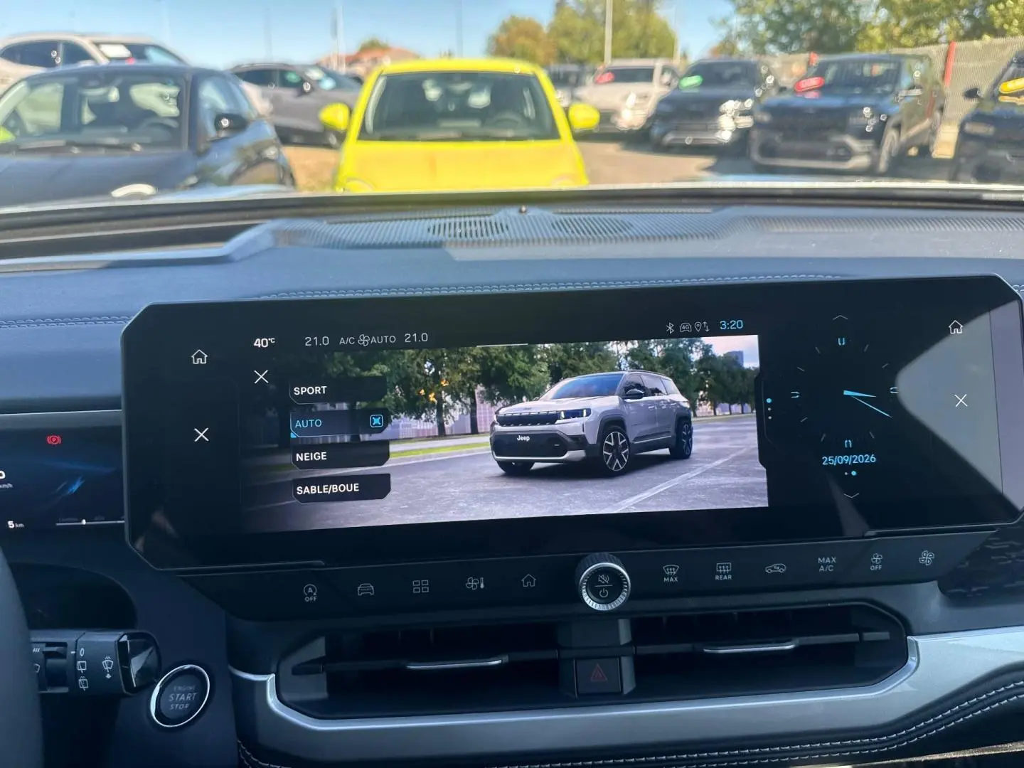 Vue intérieure centrée sur l'écran tactile affichant un Jeep Compass gris en 3/4 avant sur route.
