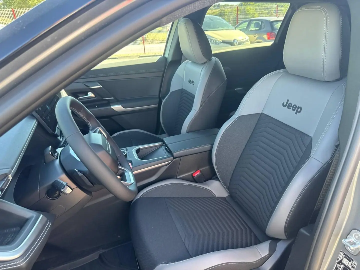 Vue intérieure côté conducteur du Jeep Compass 2026 avec sièges bicolores gris et noirs marqués Jeep.
