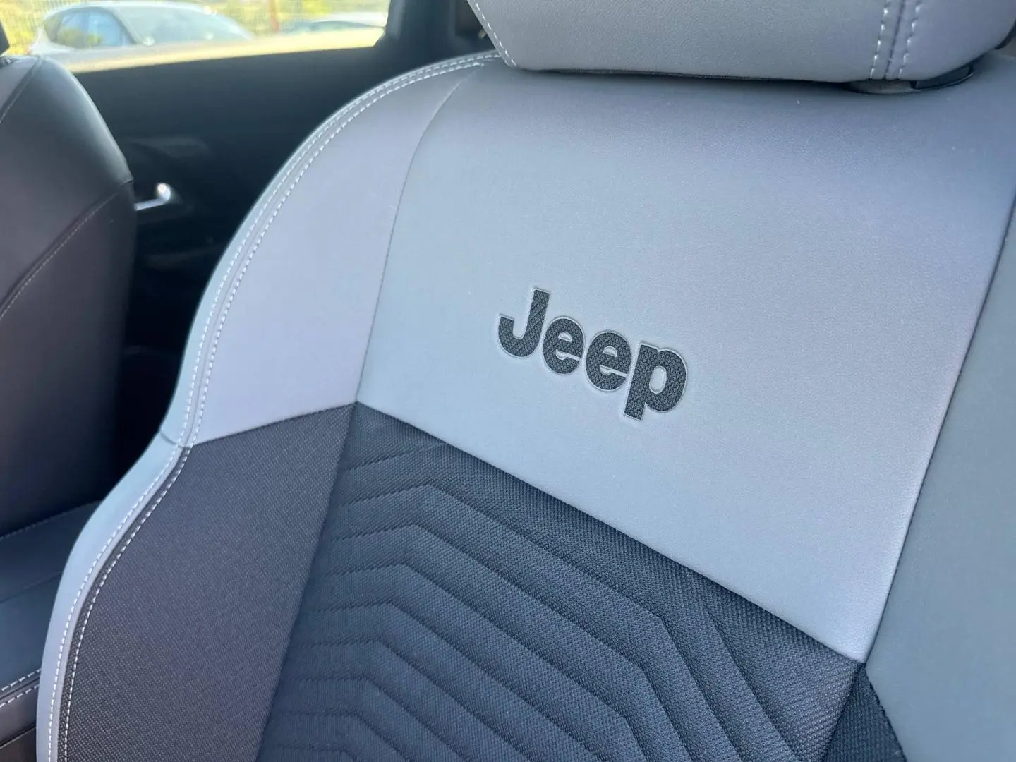 Gros plan sur le siège avant gris et noir du Jeep Compass 2026 avec logo Jeep brodé, intérieur moderne et soigné.