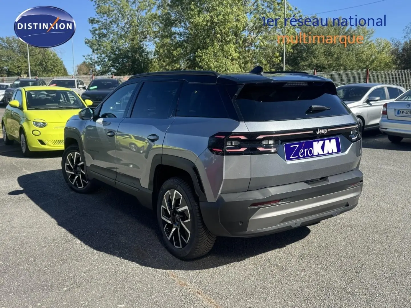 Jeep Compass Yosemite gris avec toit noir, vue 3/4 arrière côté gauche sur parking en extérieur.