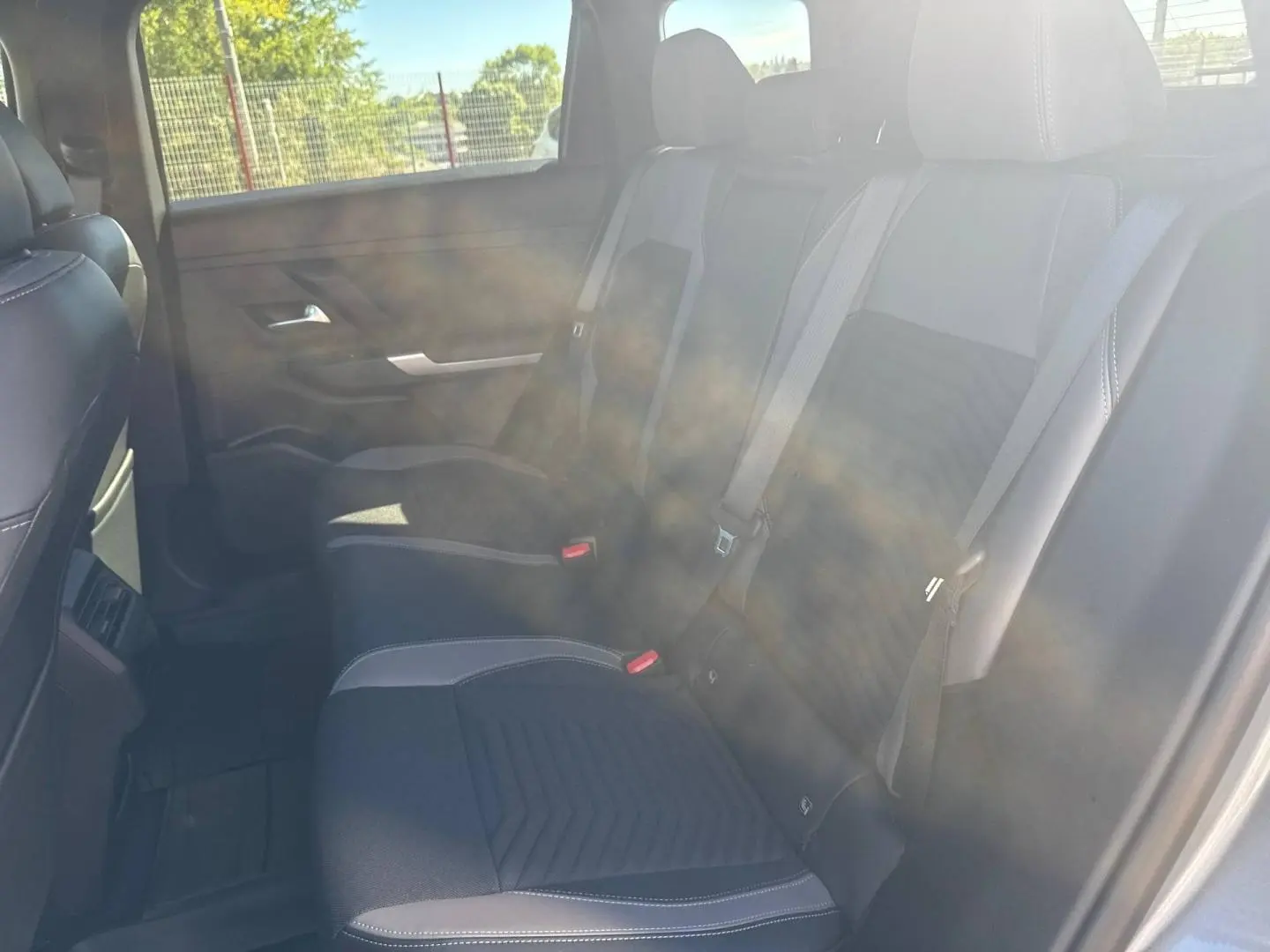 Vue latérale intérieure arrière du Jeep Compass 2026 avec sièges tissu noir et surpiqûres claires, ceintures grises visibles.