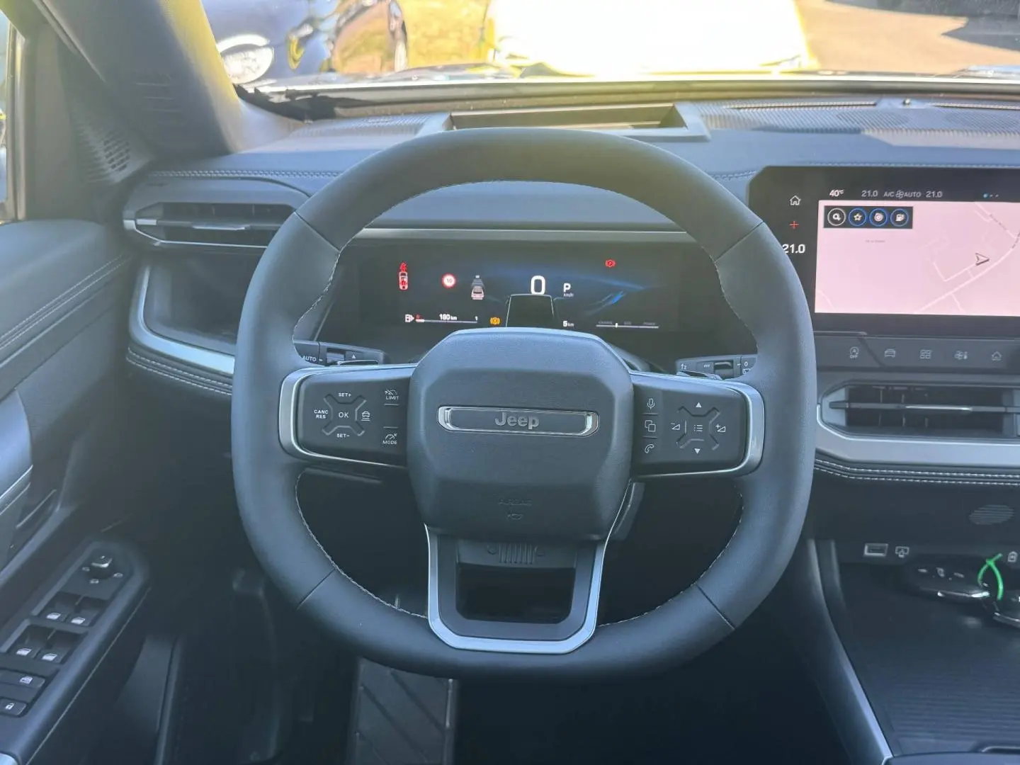 Vue intérieure frontale du volant noir du Jeep Compass 2026 avec tableau de bord numérique et écran tactile.