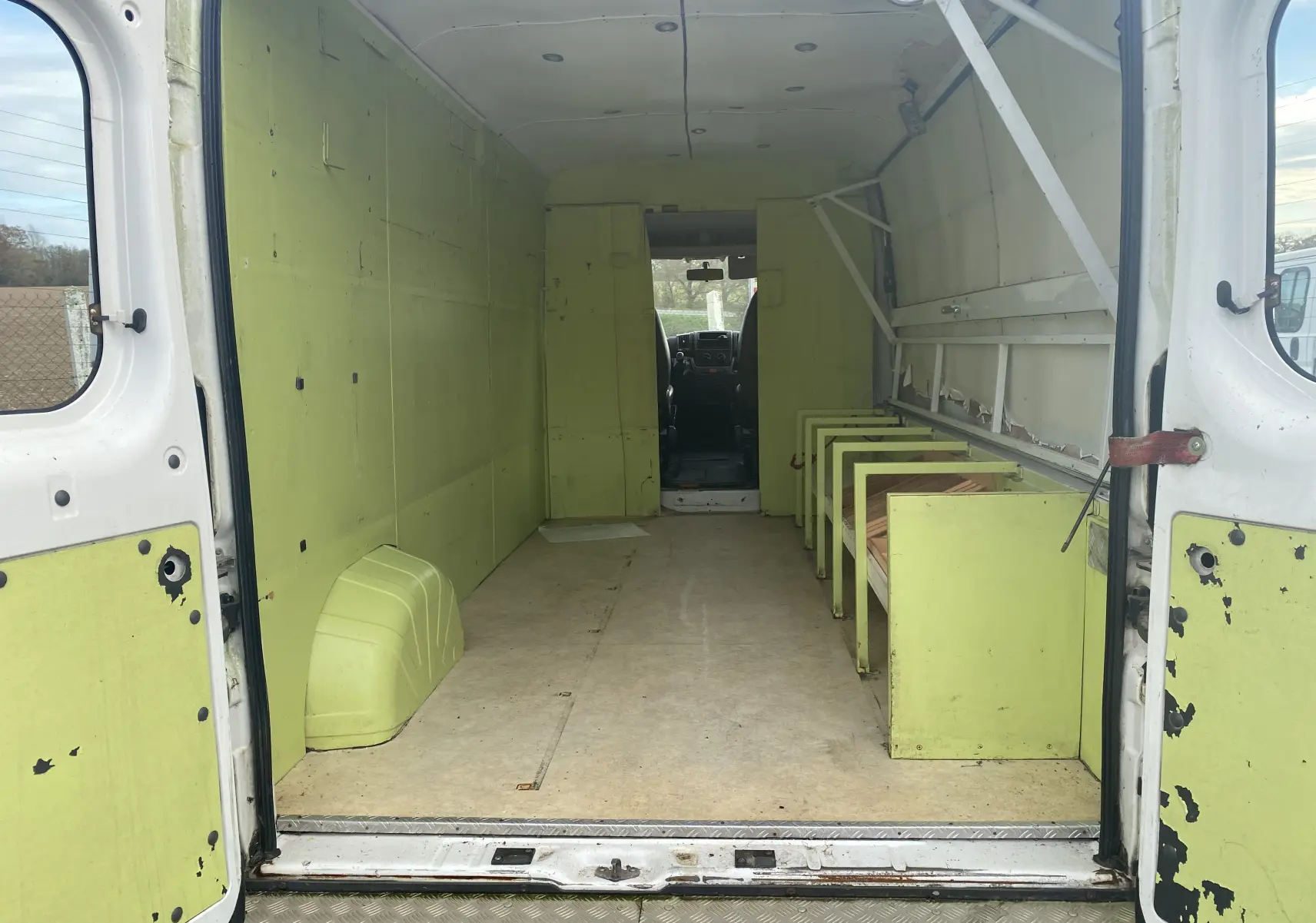 Vue intérieure arrière du Citroën Jumper blanc 2011 avec aménagements verts usés et plancher en bois.