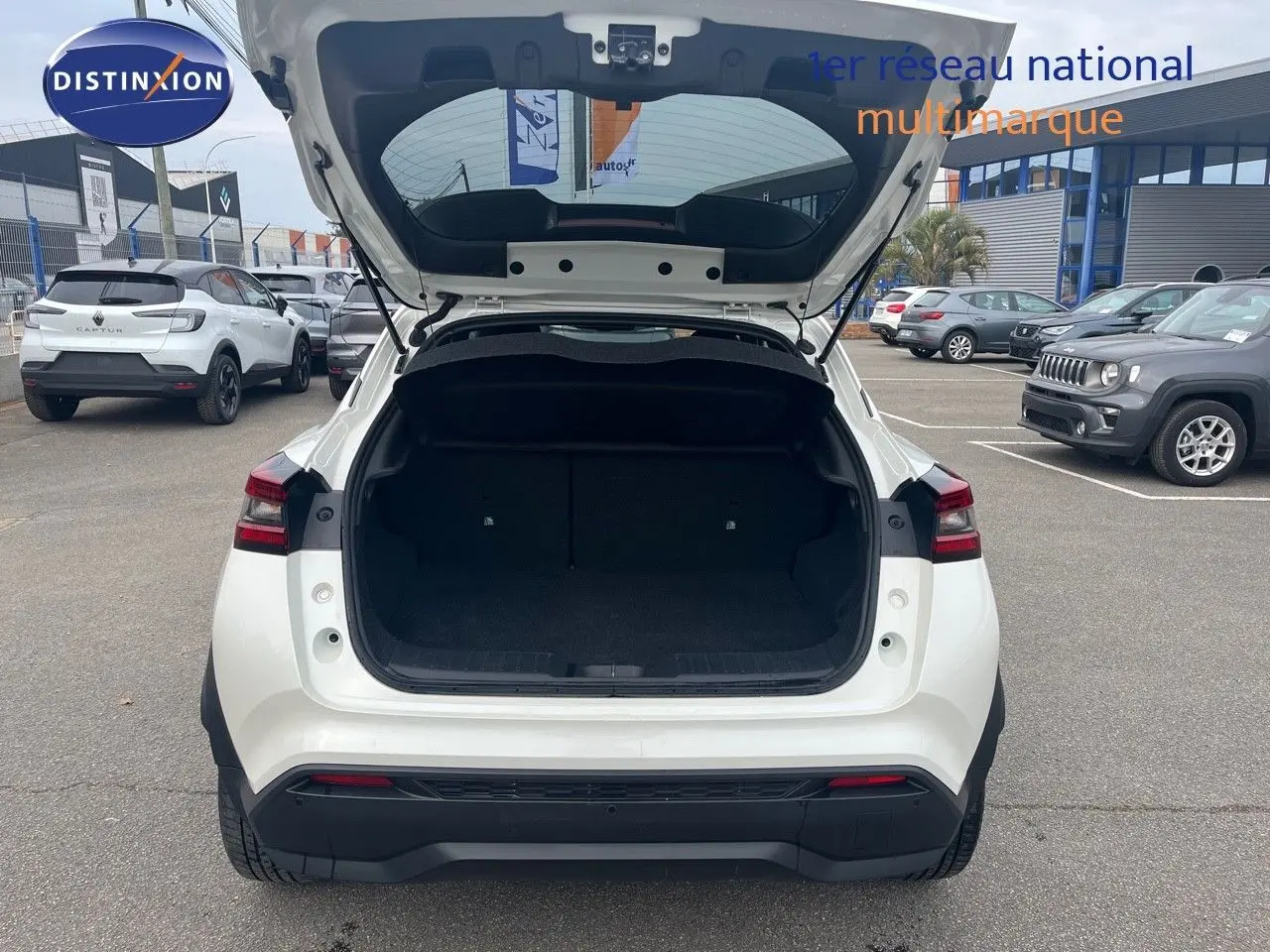 Vue arrière d'un Nissan Juke blanc nacré 2024 avec coffre ouvert, soulignant son espace de chargement.