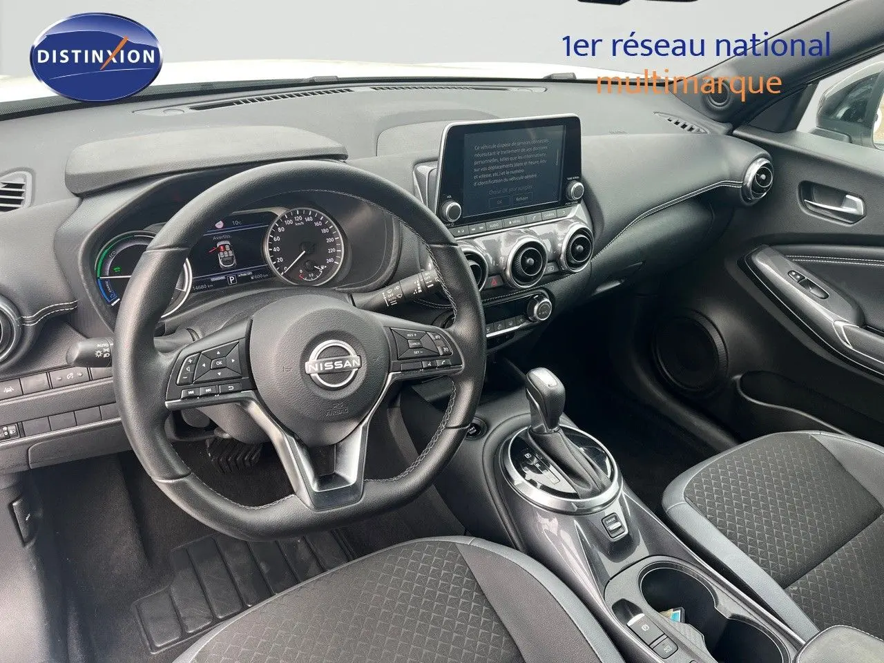 Intérieur noir du Nissan Juke 2024, vue du poste de conduite avec volant multifonction et écran tactile central.