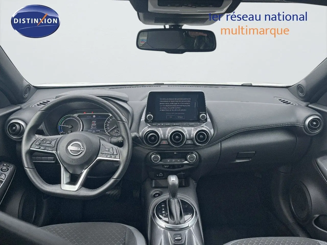 Tableau de bord et volant noir du Nissan Juke 2024, vue frontale intérieure avec écran tactile central et aérateurs ronds.