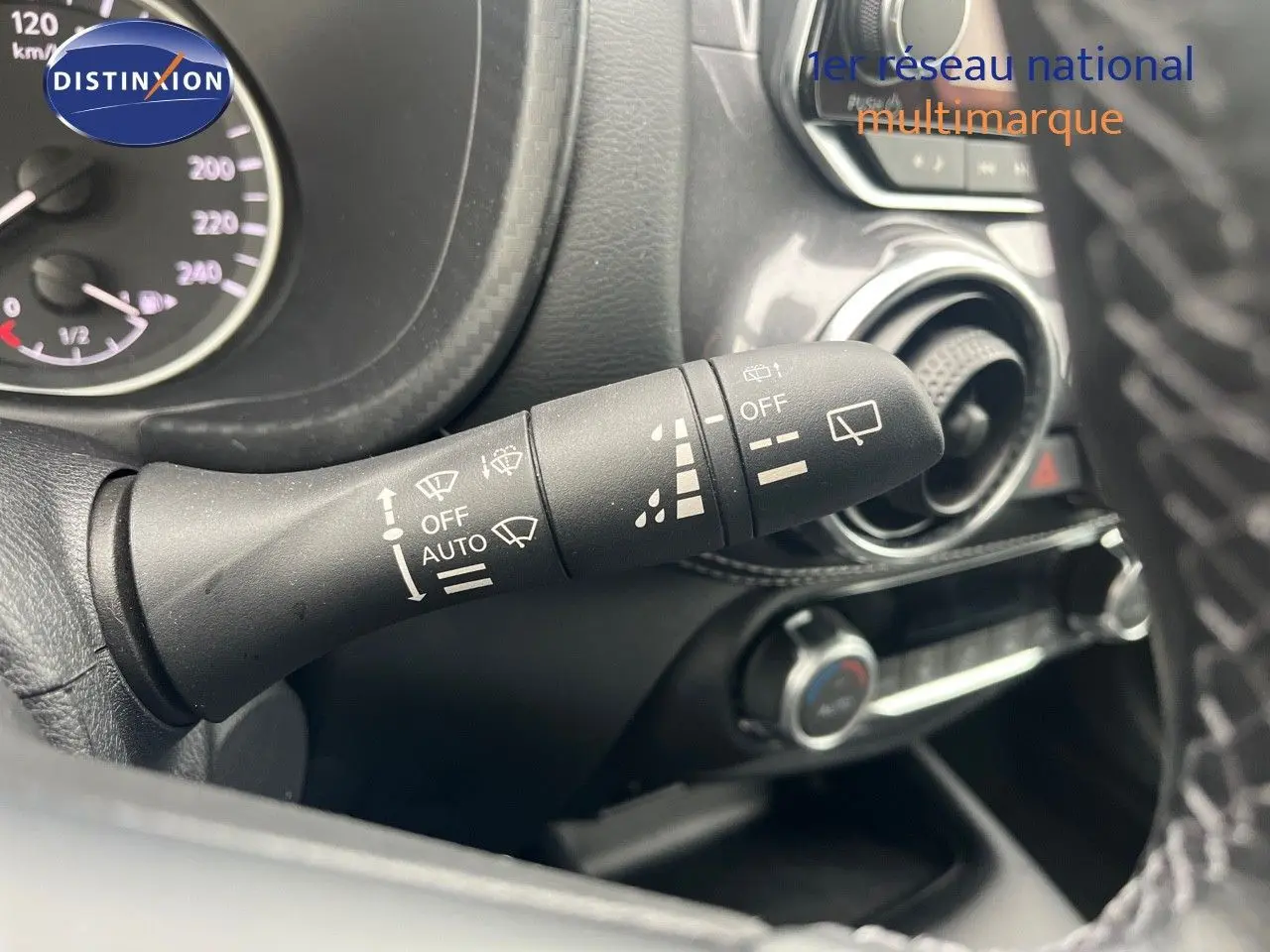 Gros plan sur la commande d'essuie-glace à gauche du volant dans l'habitacle du Nissan Juke blanc nacré 2024.