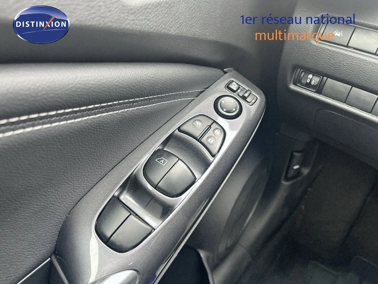 Gros plan sur les commandes électriques de la porte côté conducteur du Nissan Juke blanc nacré 2024.