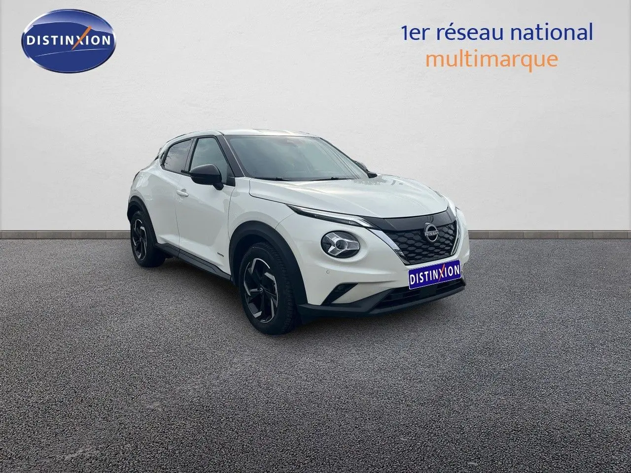 Nissan Juke blanc nacré métal en 3/4 avant droit, avec jantes noires et toit contrasté noir.
