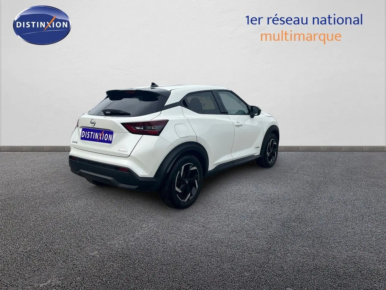 Nissan Juke blanc nacré métal vu en 3/4 arrière droit, soulignant ses jantes noires et lignes modernes.