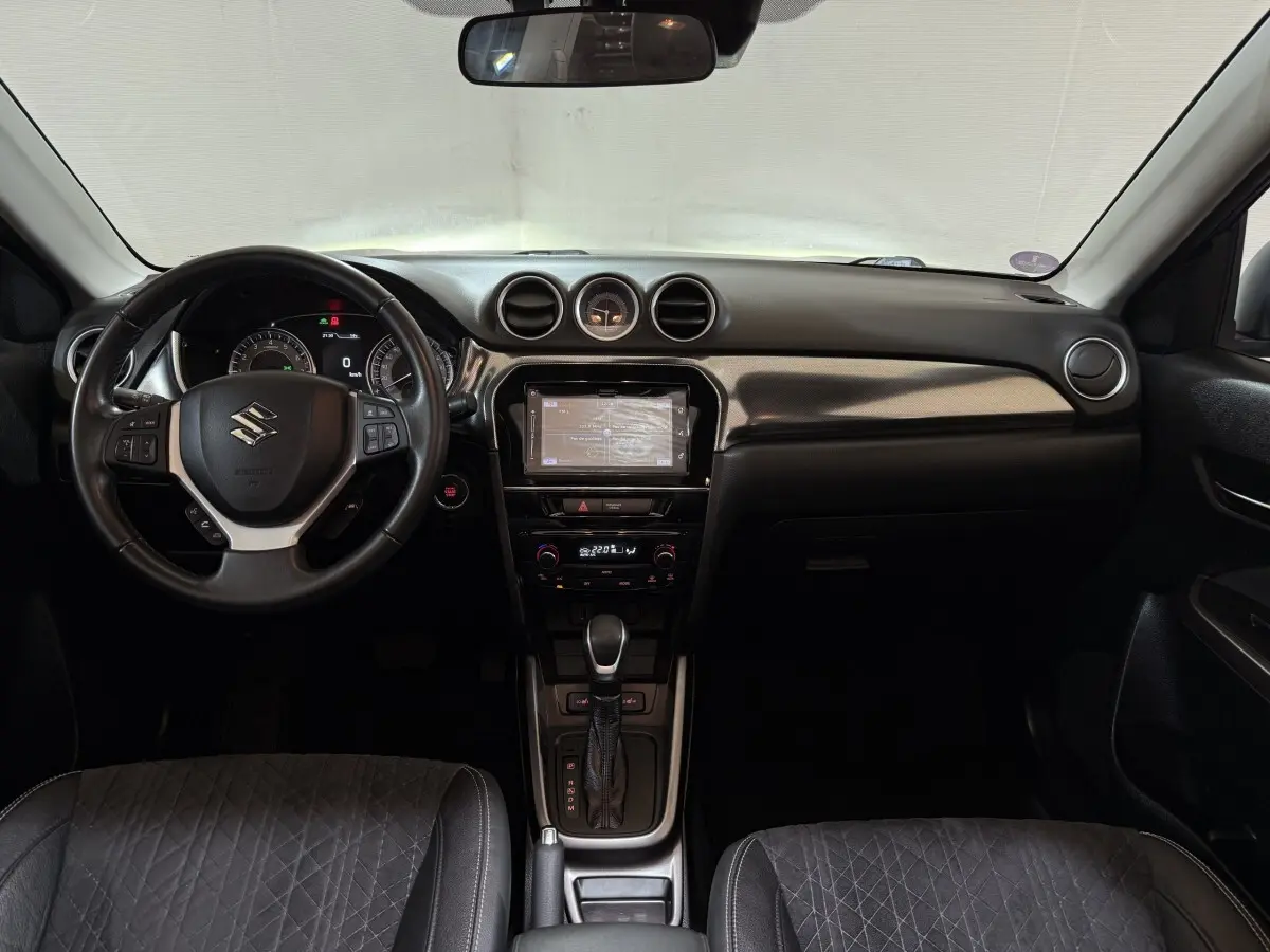Intérieur noir du Suzuki Vitara 2022 vu de face, tableau de bord avec écran tactile et volant multifonctions cuir.