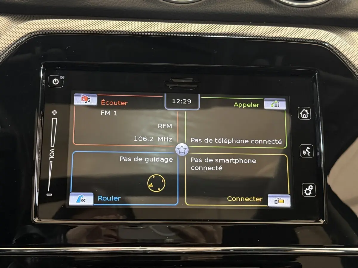 Écran tactile central du Suzuki Vitara noir 2022 affichant radio FM et options de connexion smartphone et téléphone.