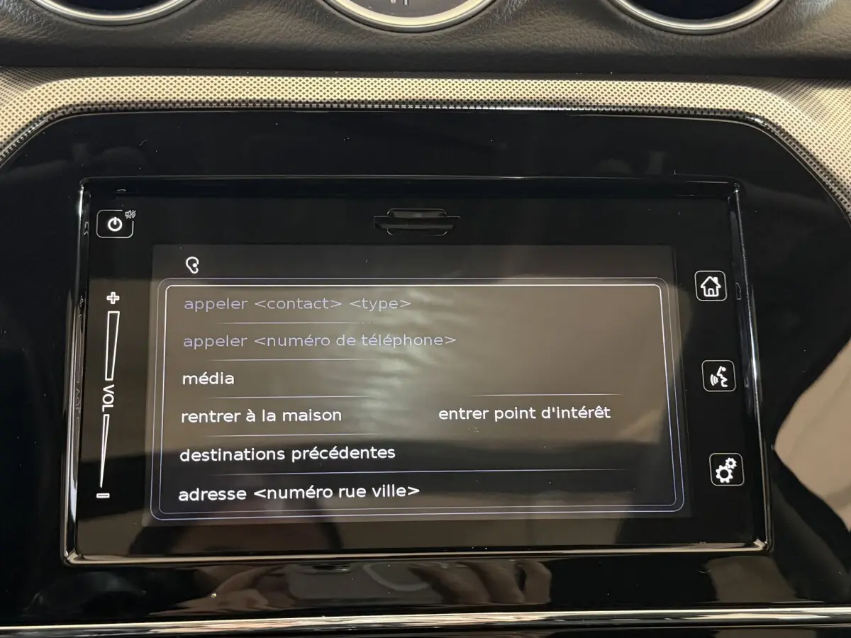 Écran tactile central du tableau de bord du Suzuki Vitara noir 2022 affichant le menu vocal de navigation et médias.