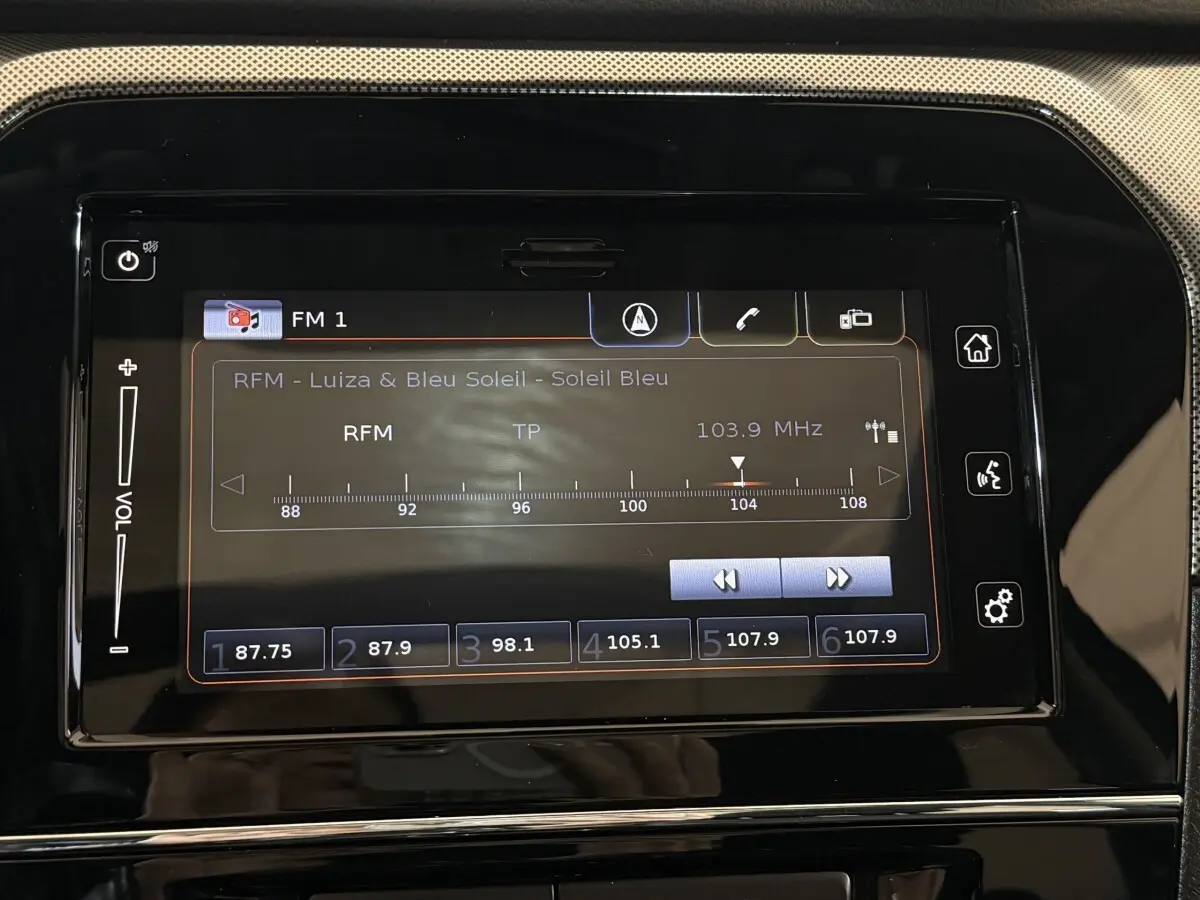 Écran tactile central du tableau de bord du Suzuki Vitara noir 2022 affichant la radio FM 103,9 MHz.