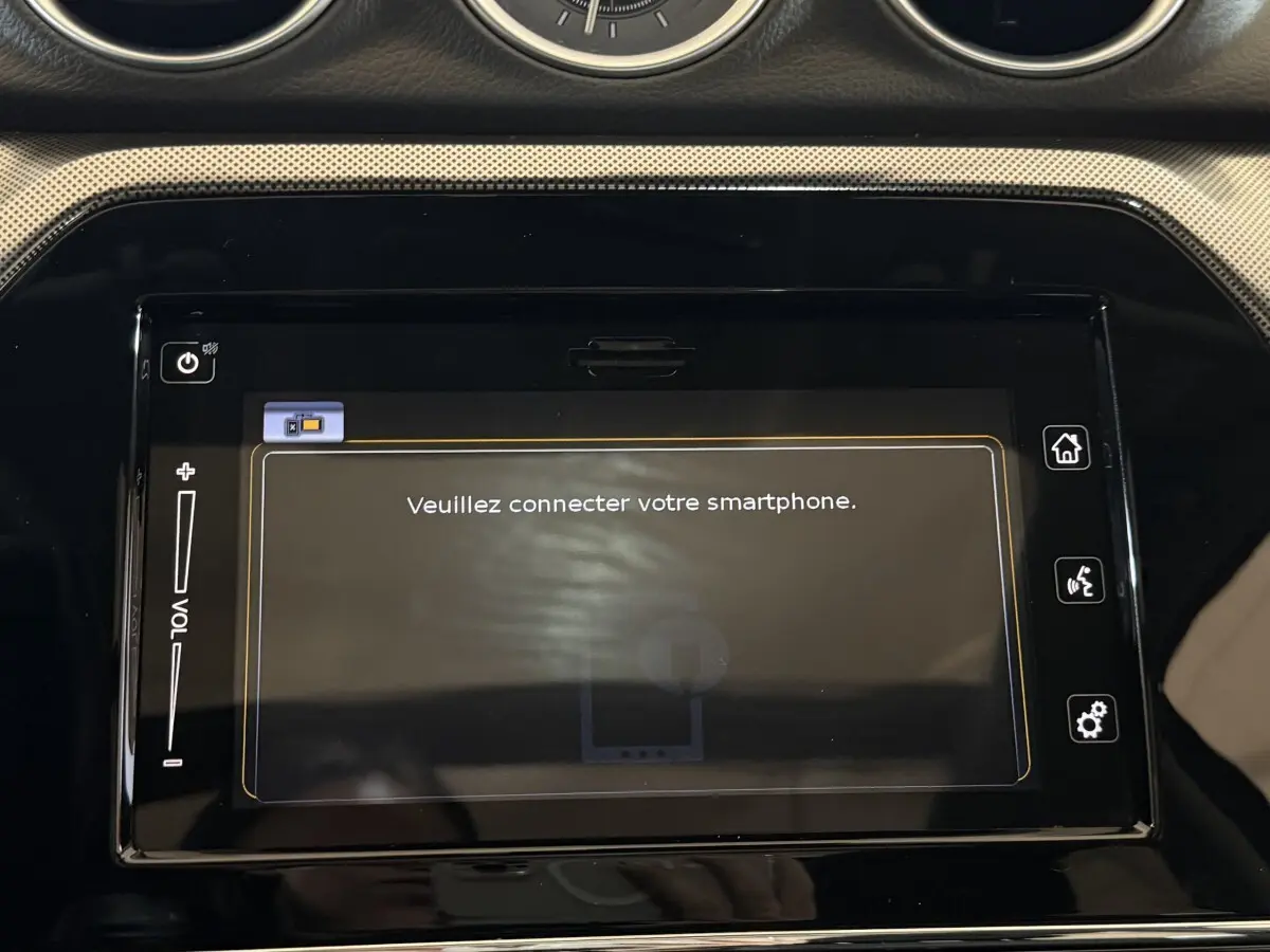 Écran tactile central noir affichant "Veuillez connecter votre smartphone" dans l'habitacle du Suzuki Vitara noir.