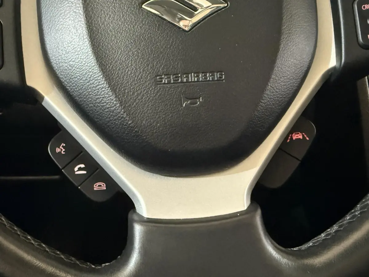 Gros plan sur le volant cuir noir et aluminium du Suzuki Vitara 1.5 Dualjet hybrid STYLE 2022 avec commandes intégrées.