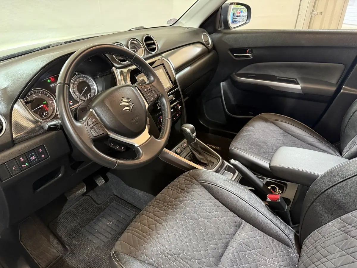 Intérieur noir du Suzuki Vitara 2022 vu côté conducteur, volant cuir multifonctions et console centrale avec boîte auto.
