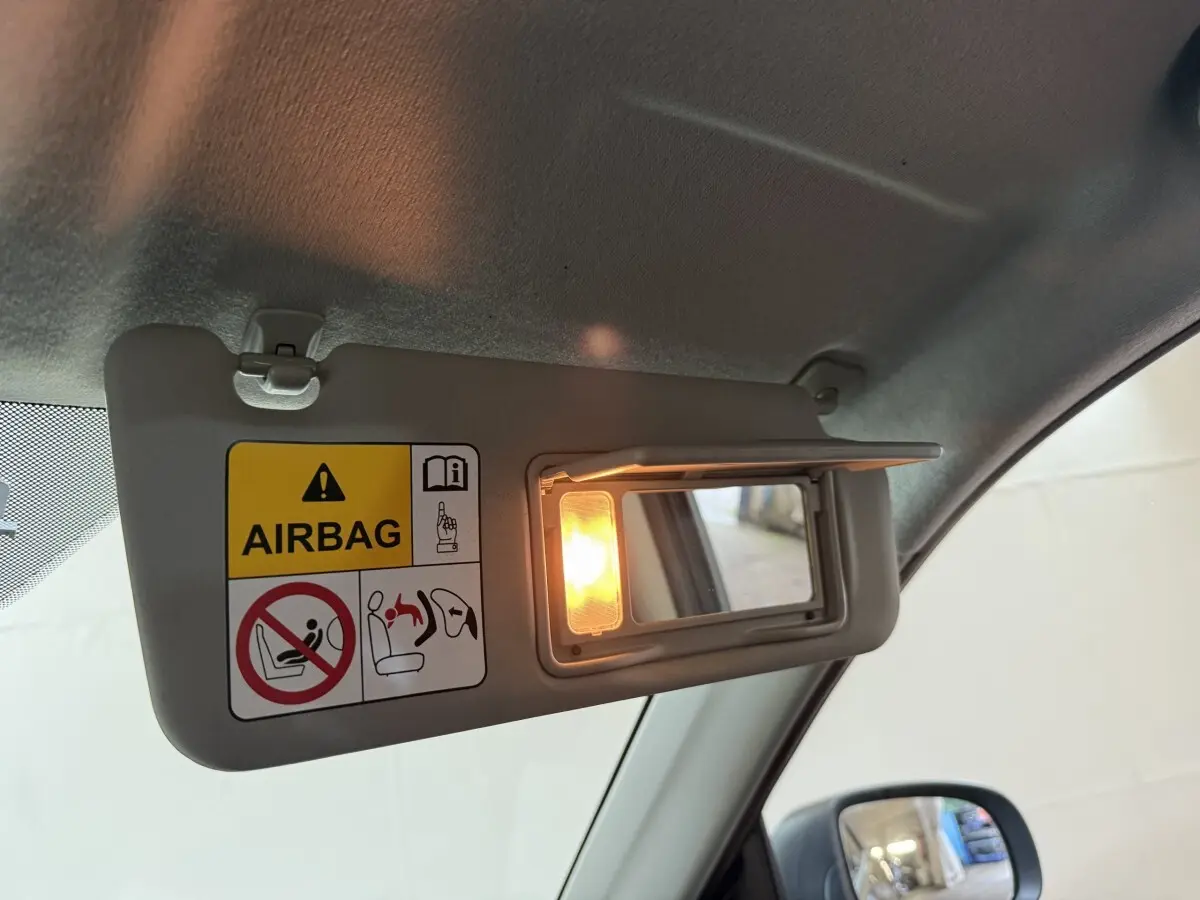 Détail du pare-soleil côté conducteur du Suzuki Vitara noir 2022 avec miroir éclairé et avertissement airbag.
