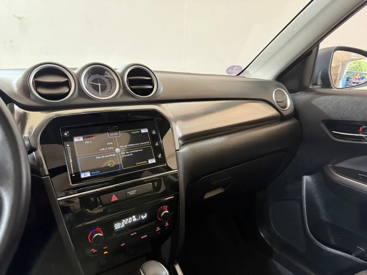 Intérieur du Suzuki Vitara 1.5 Hybrid 2022 vu côté passager, tableau de bord noir avec écran tactile et horloge centrale.