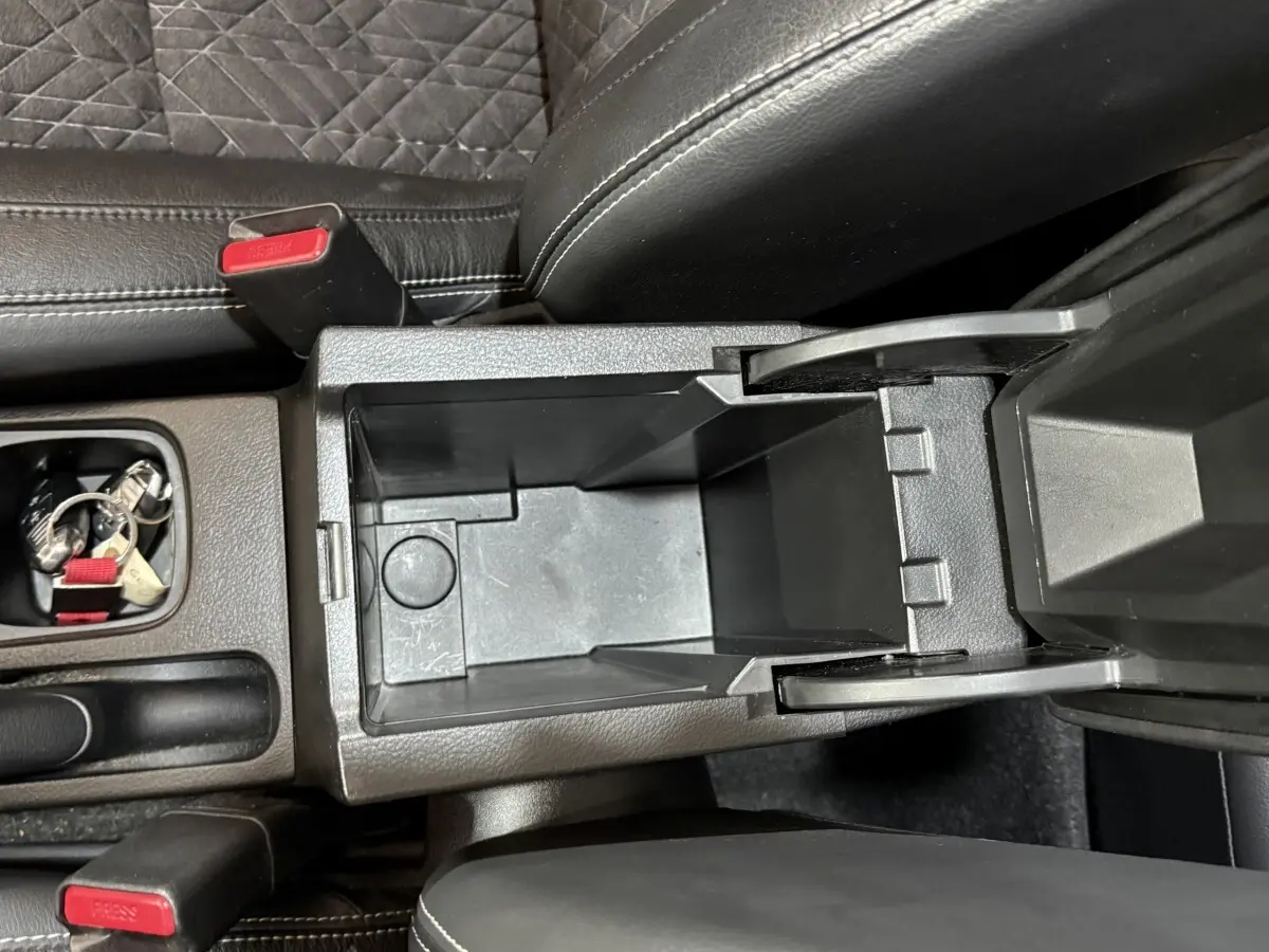 Vue plongeante sur la console centrale noire ouverte du Suzuki Vitara 1.5 Hybrid avec sièges en cuir noir.