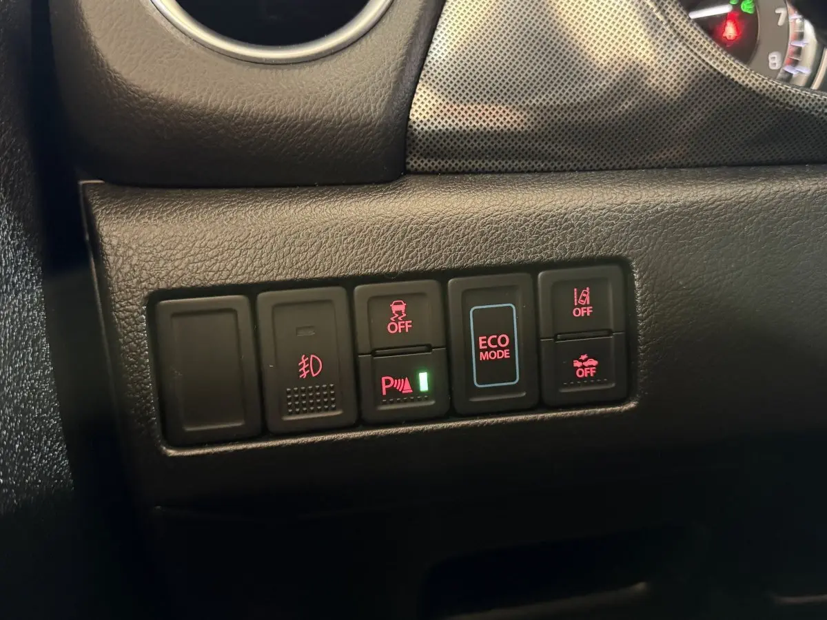 Gros plan sur les commandes du tableau de bord du Suzuki Vitara noir 2022, avec boutons d'assistance et mode ECO éclairés.