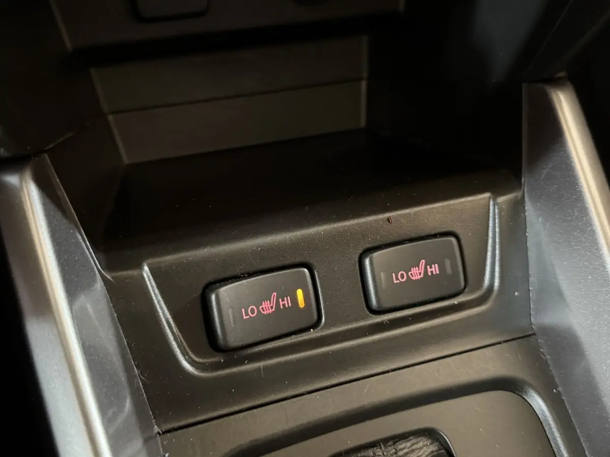 Gros plan sur les commandes de chauffage des sièges avant du Suzuki Vitara noir 2022, bouton gauche activé.