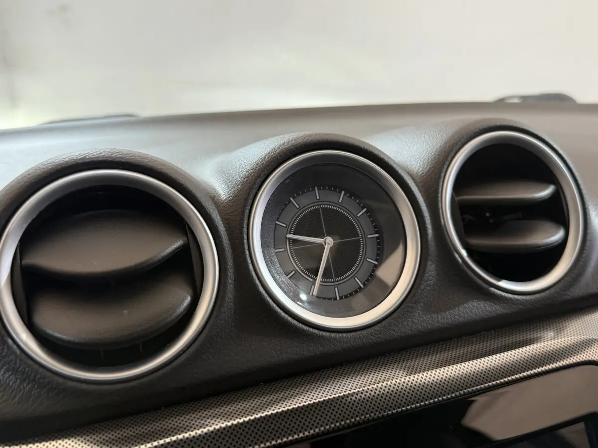Gros plan sur l'horloge ronde et les aérateurs circulaires du tableau de bord noir du Suzuki Vitara 2022.