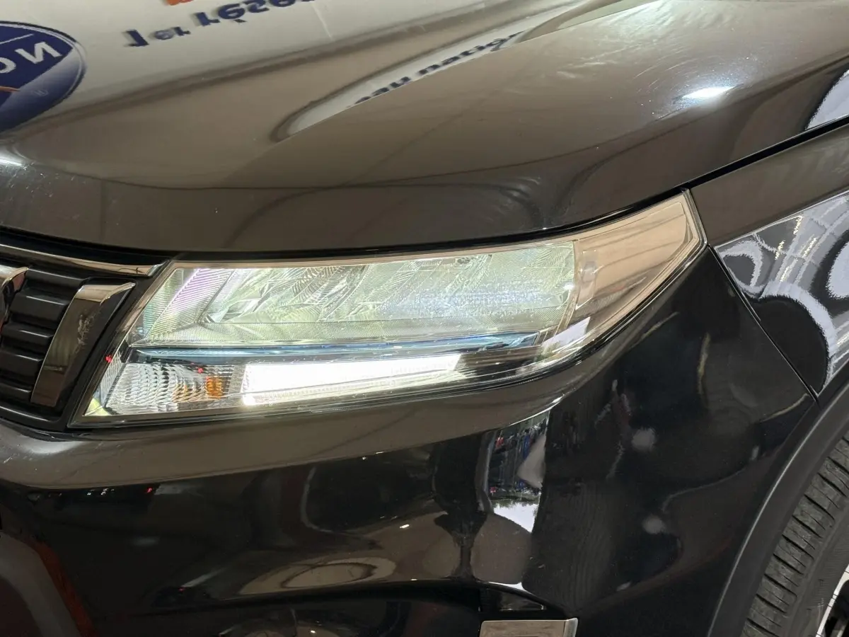 Gros plan sur le phare avant droit du Suzuki Vitara noir 2022, mettant en valeur ses feux LED et la calandre chromée.