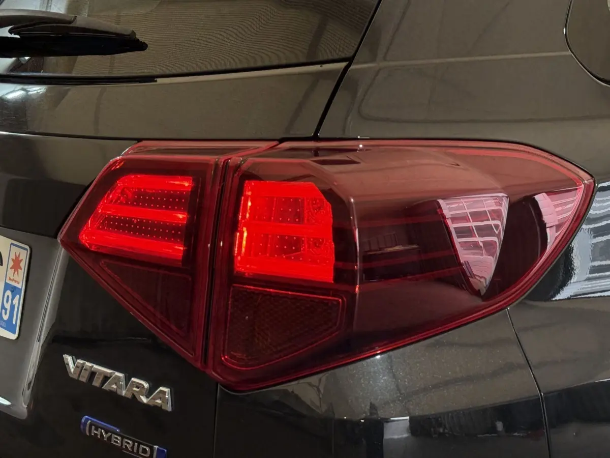 Feu arrière droit rouge sur Suzuki Vitara noir hybride 2022, avec logo VITARA visible près de la plaque arrière.