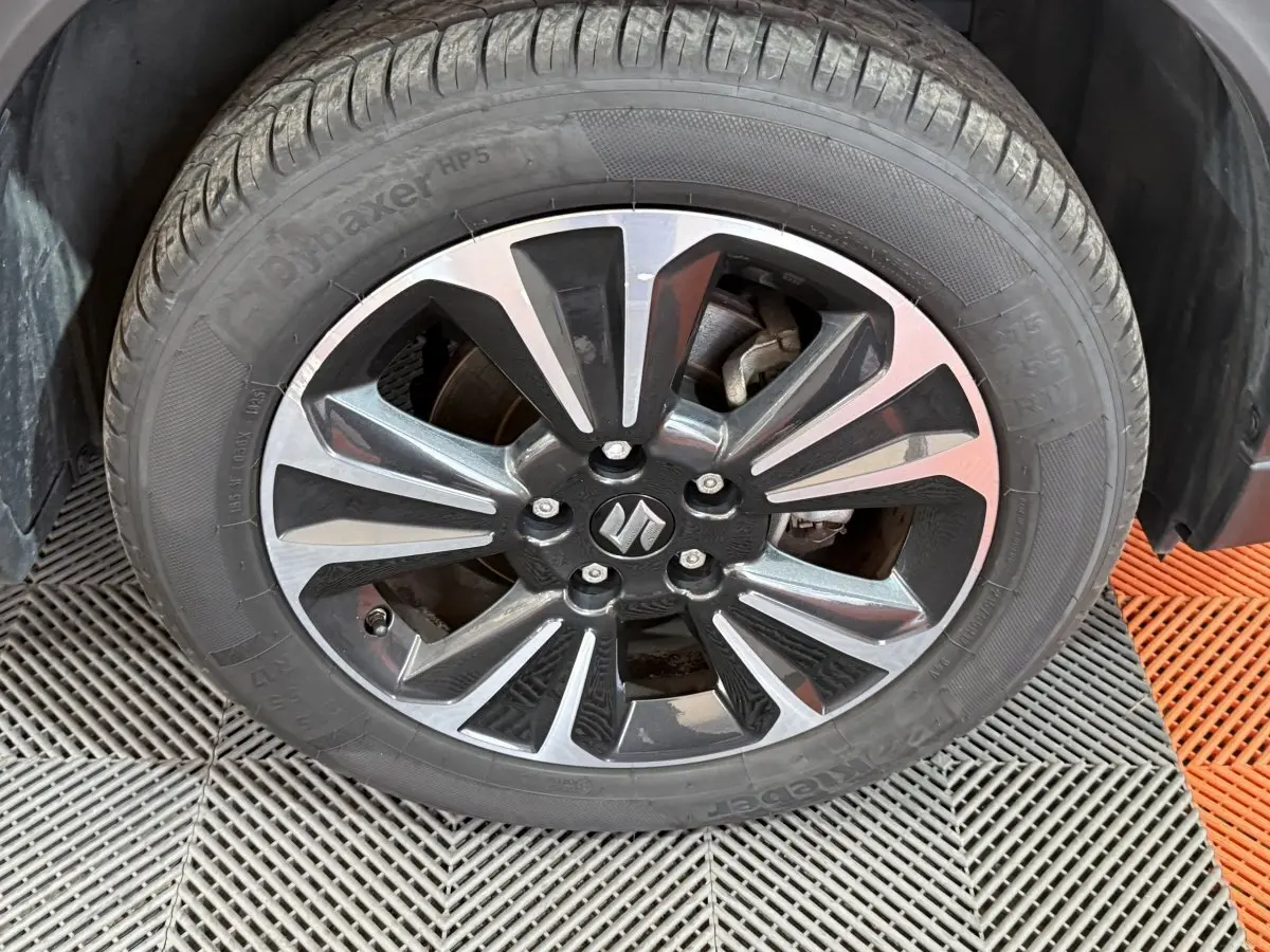 Gros plan sur la jante alliage bicolore noire et argentée avec logo Suzuki du Suzuki Vitara 2022 noir.