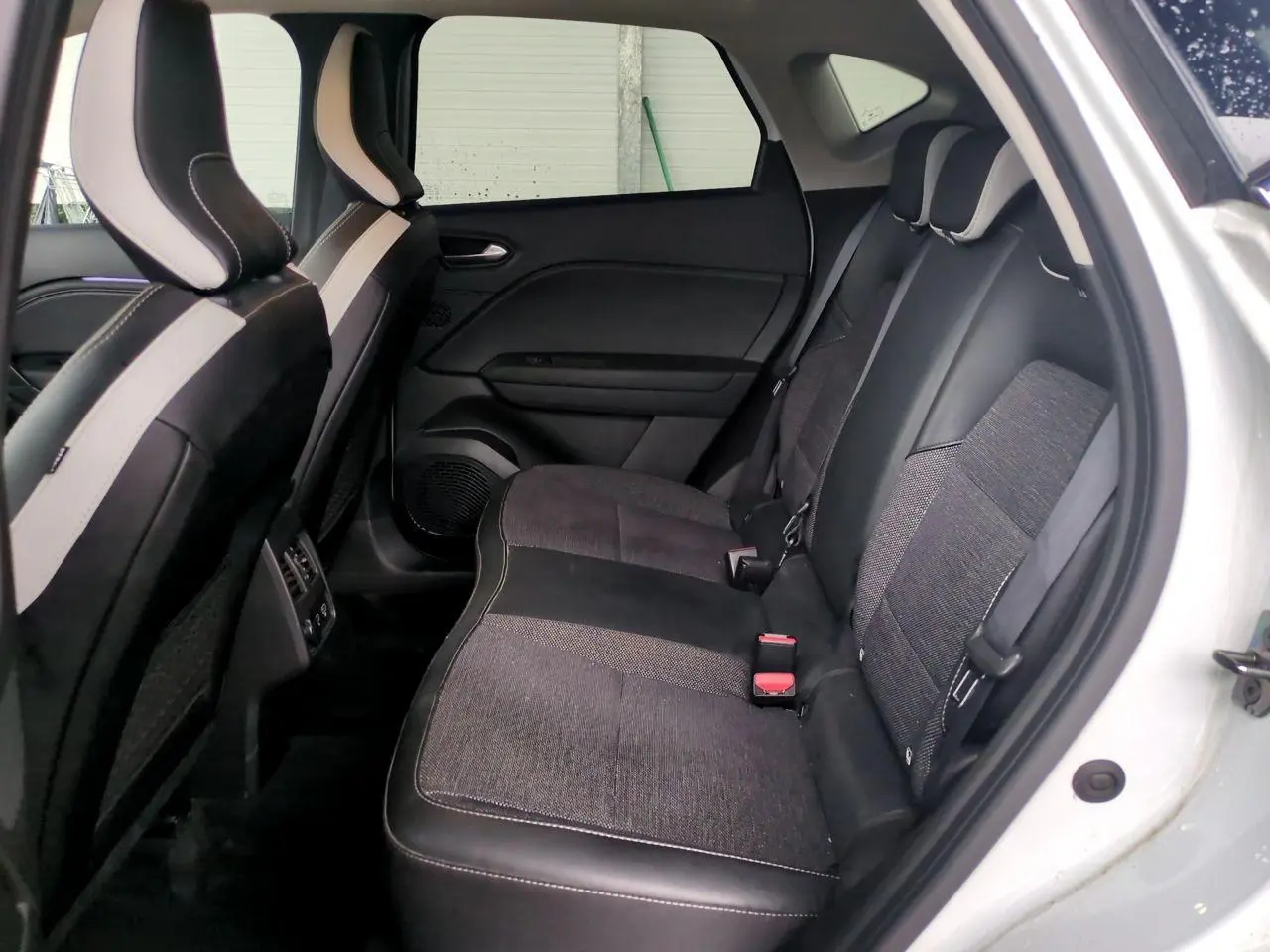 Vue intérieure côté droit de la banquette arrière noire et grise du Renault Captur blanc 2024 avec appuis-tête réglables.