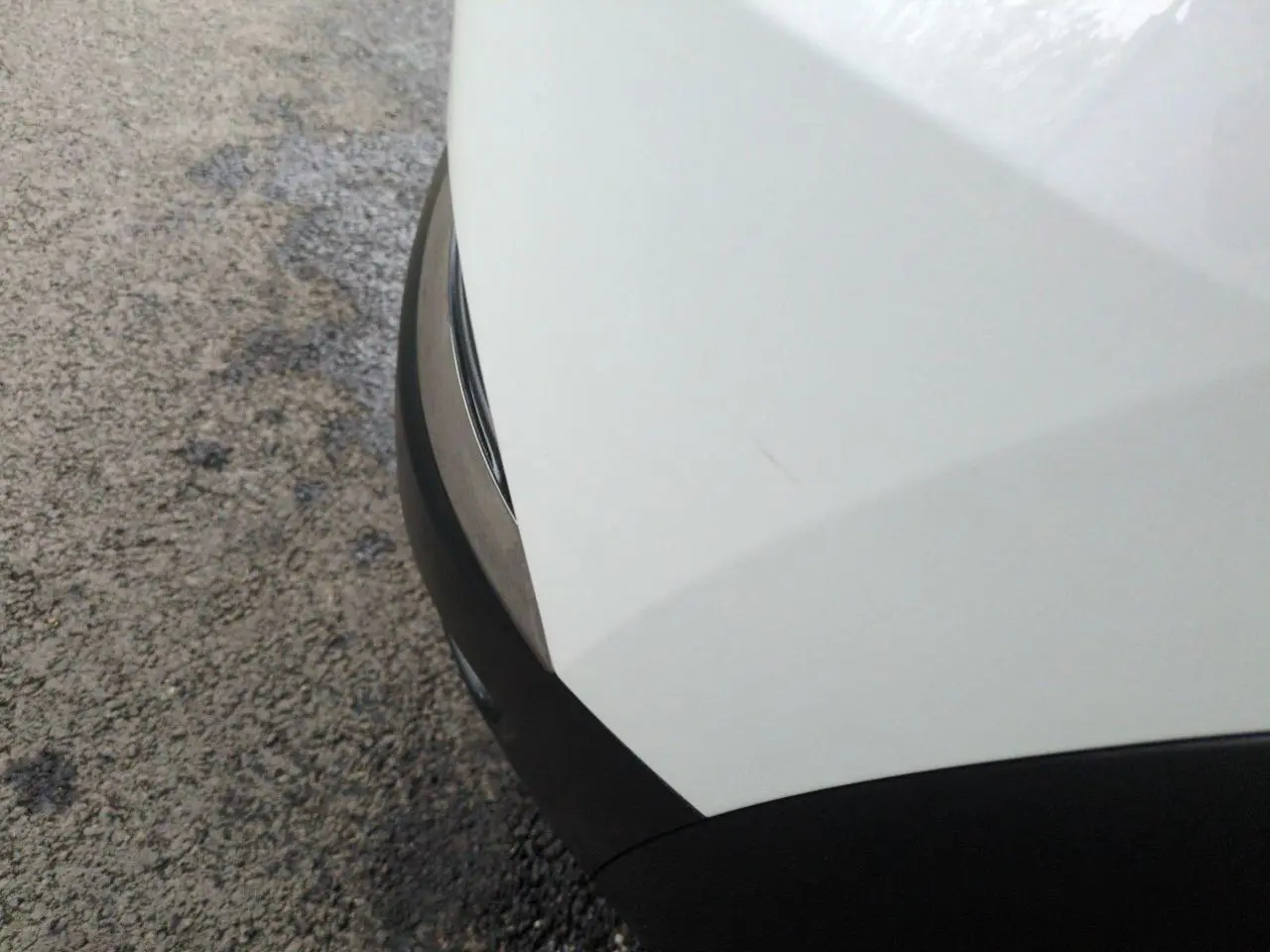 Gros plan sur l'angle avant droit blanc du Renault Captur 2024 avec protection noire et jonc chromé.