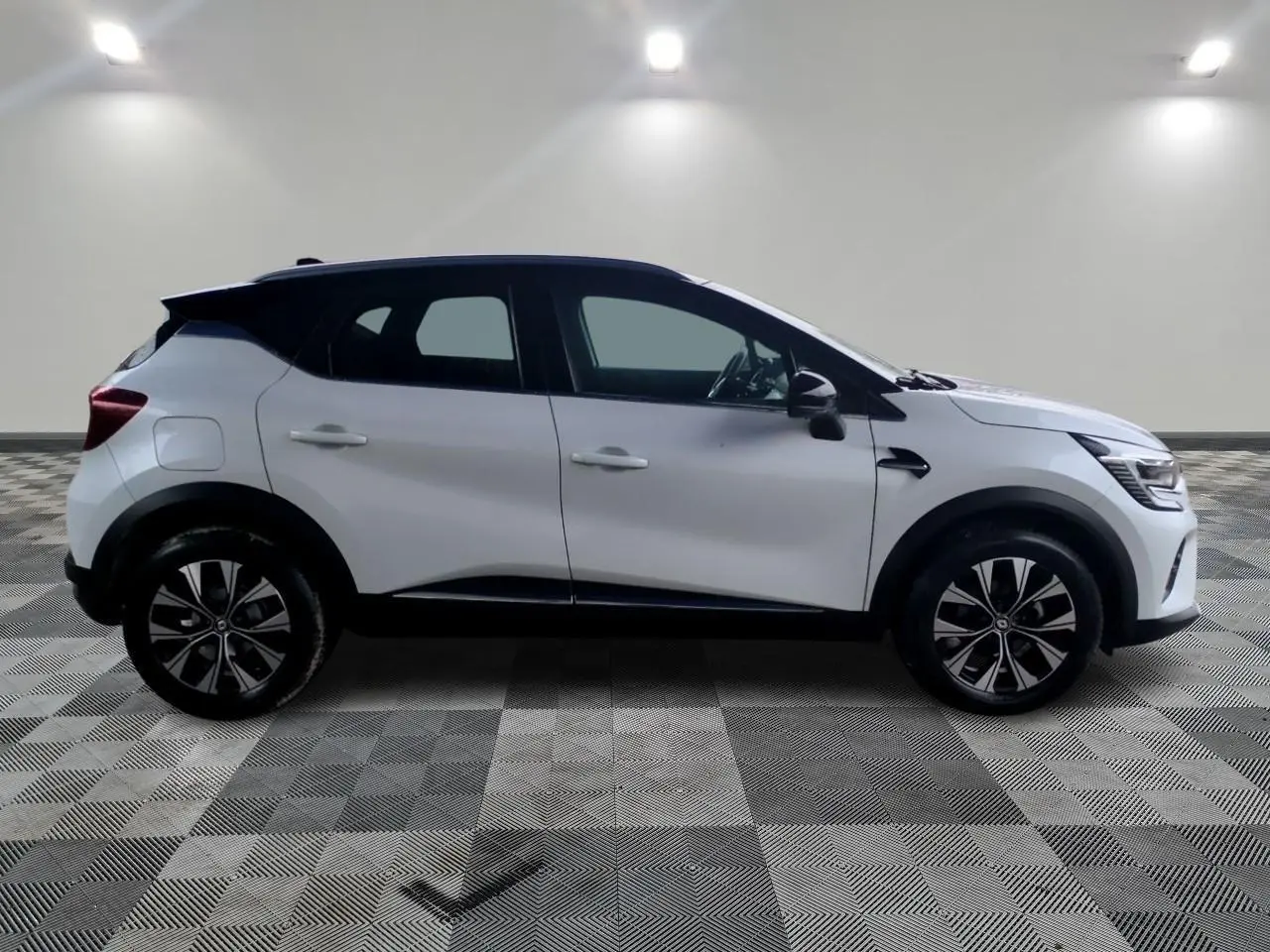Profil droit du Renault Captur blanc avec toit noir et jantes alliage 18 pouces Pasadena diamantées.