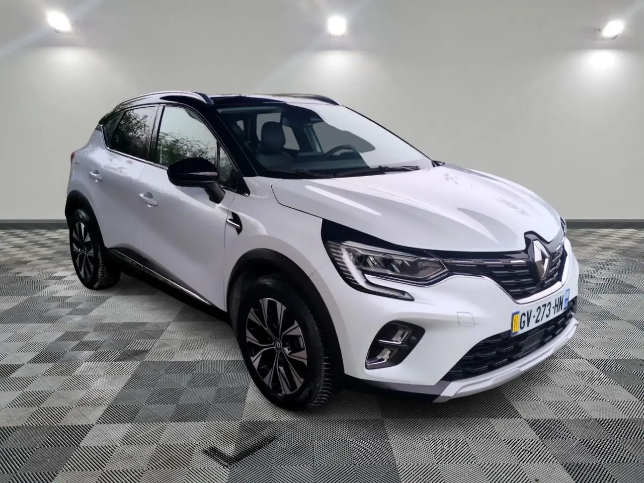 Renault Captur blanc vue 3/4 avant droit avec jantes alliage et toit noir contrasté en intérieur neutre.