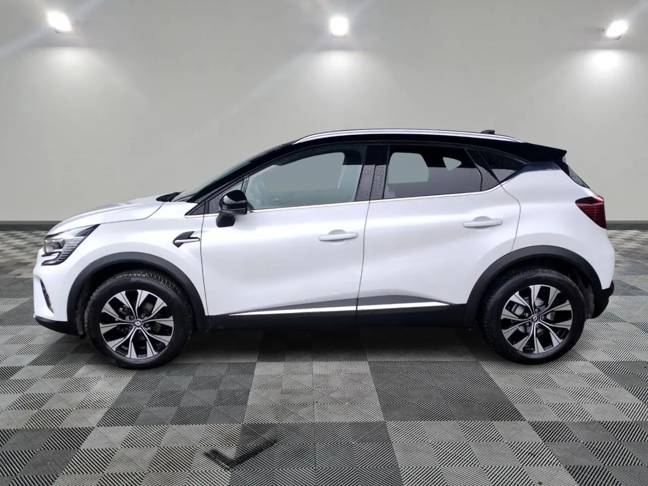 Profil droit d'un Renault Captur blanc 2024 avec toit noir, jantes alliage 18 pouces et protections noires.