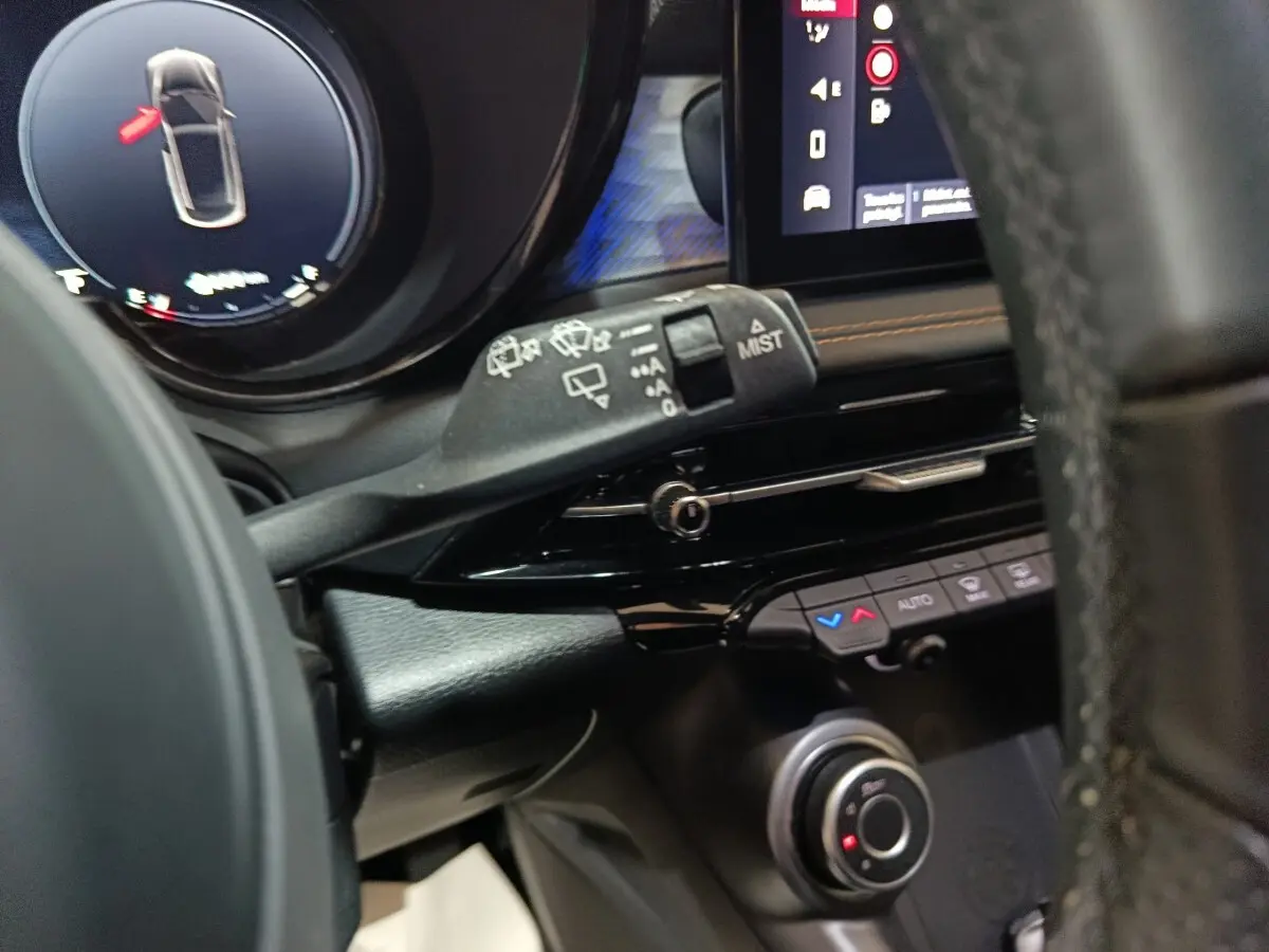 Gros plan sur la commande d’essuie-glace et le tableau de bord noir de l’Alfa Romeo Tonale bleu, avec écran tactile visible.