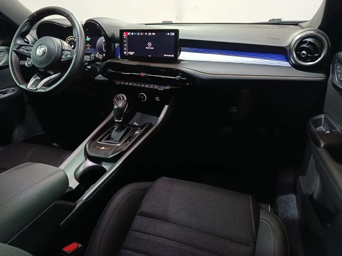 Vue intérieure côté conducteur de l'Alfa Romeo Tonale bleu, avec tableau de bord digital et console centrale moderne.