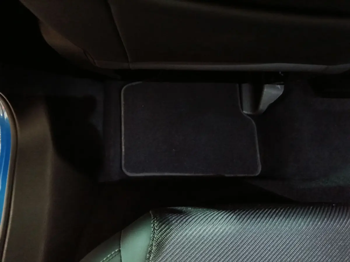 Vue intérieure du plancher côté passager avant avec tapis noir et partie de la portière bleue d’un Alfa Romeo Tonale 2023.