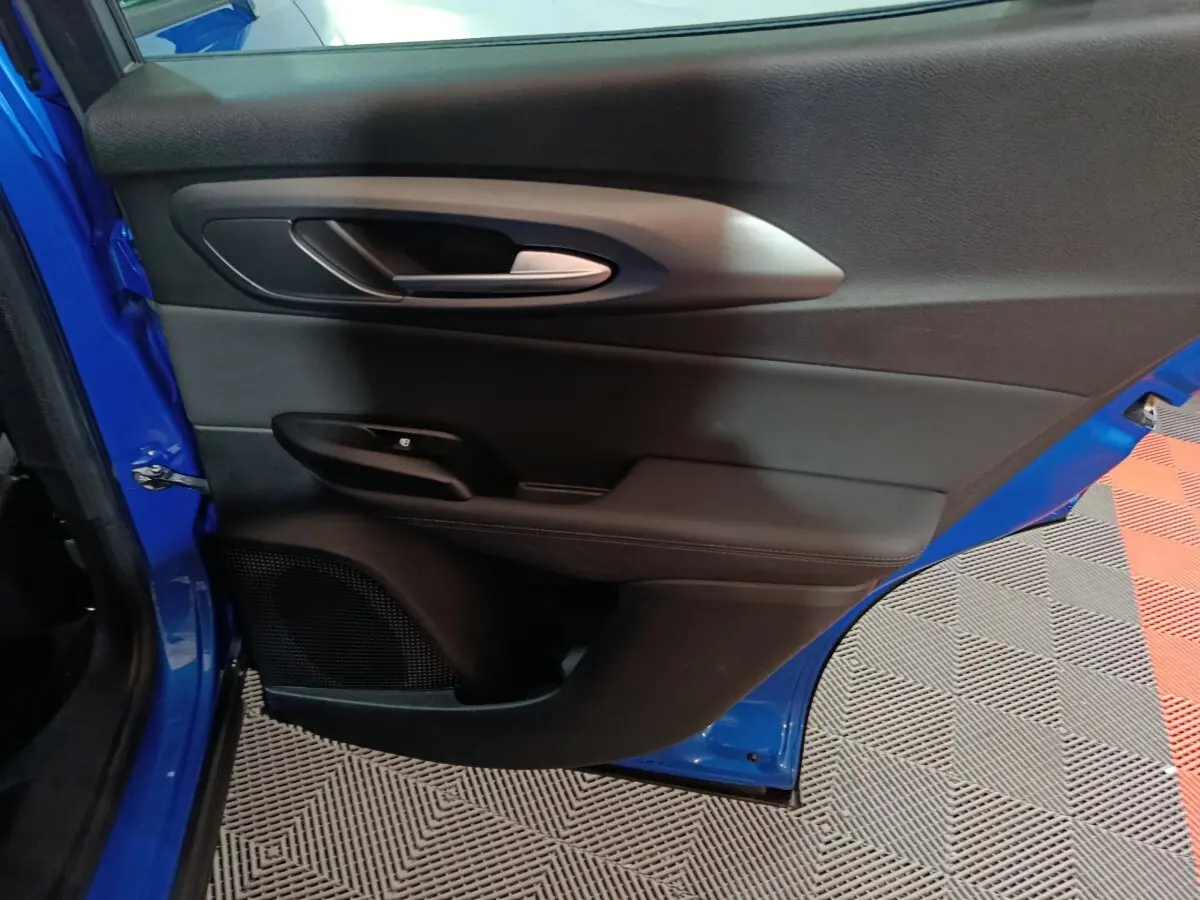 Vue rapprochée de la porte arrière gauche bleu vif de l'Alfa Romeo Tonale avec poignée intérieure argentée.