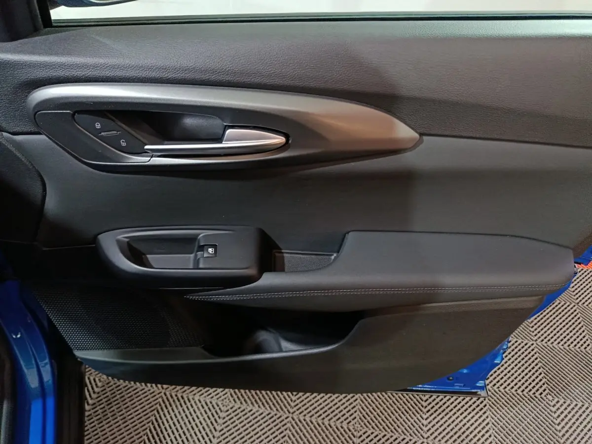 Détail de la porte côté gauche de l'Alfa Romeo Tonale bleu 2023, avec poignée argentée et commandes de verrouillage.