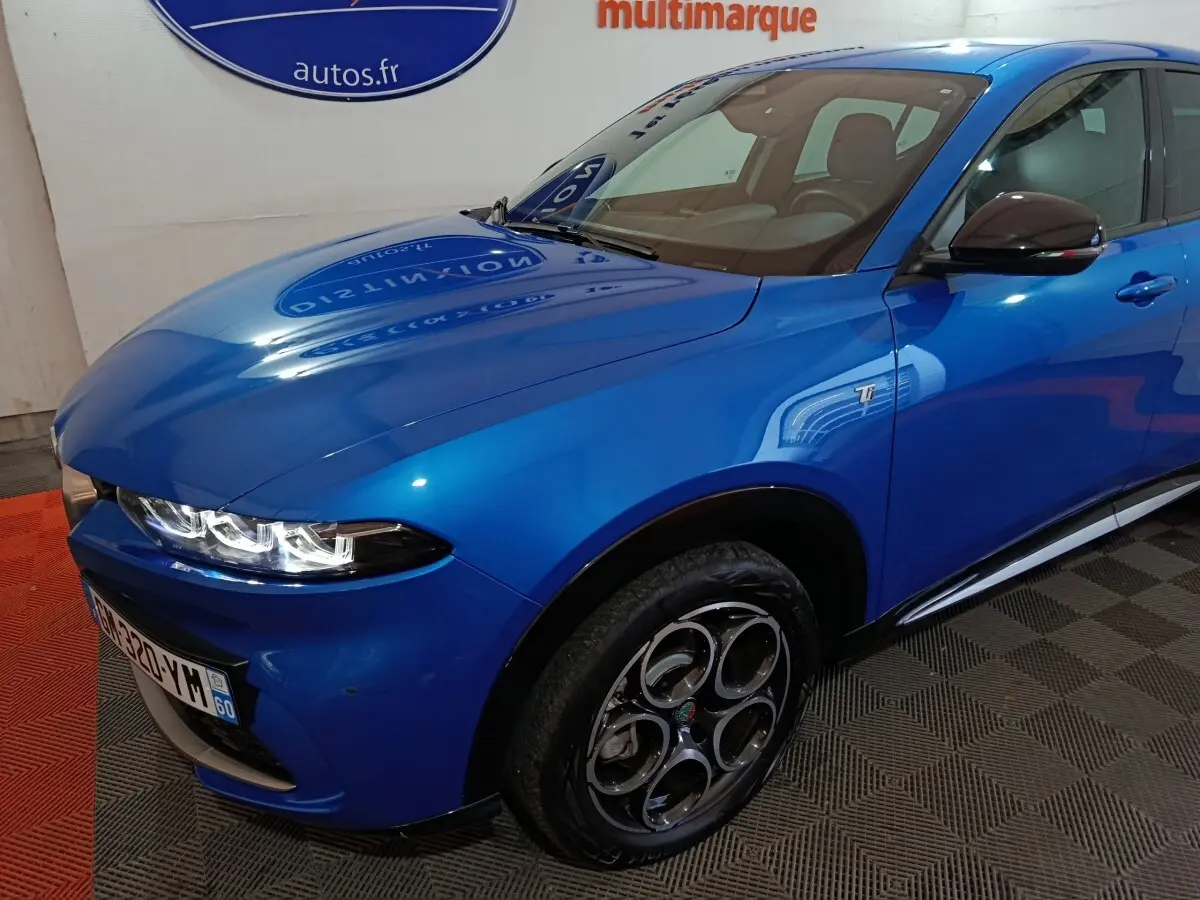 Vue 3/4 avant droit de l'Alfa Romeo Tonale bleu avec jantes distinctives et badge Ti sur l'aile avant.