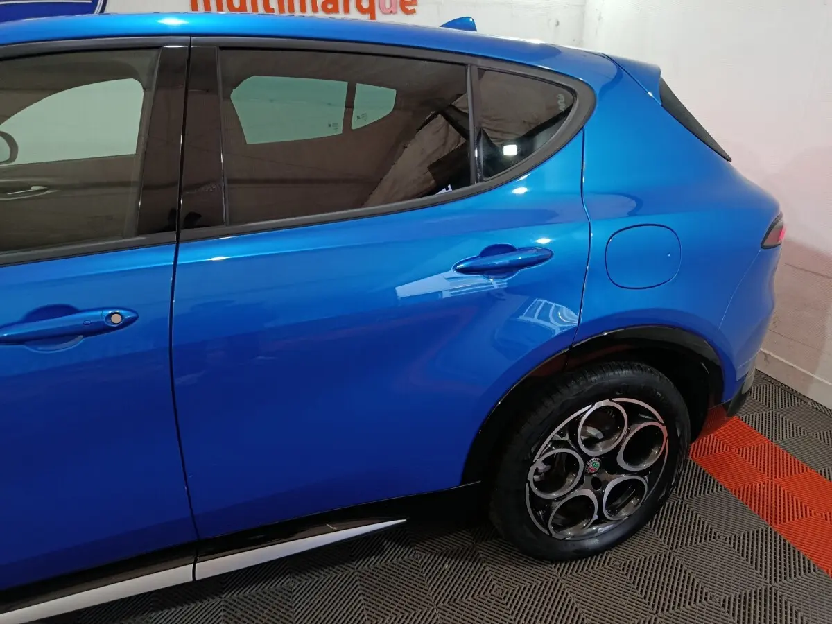 Vue latérale droite d'une Alfa Romeo Tonale 2023 bleu électrique, mettant en valeur la porte arrière et la trappe à carburant.