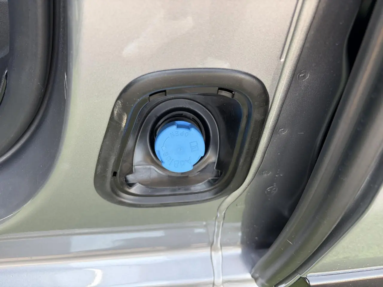 Gros plan sur le bouchon bleu AdBlue du réservoir d’un Citroën Jumpy gris acier métal, côté gauche ouvert.