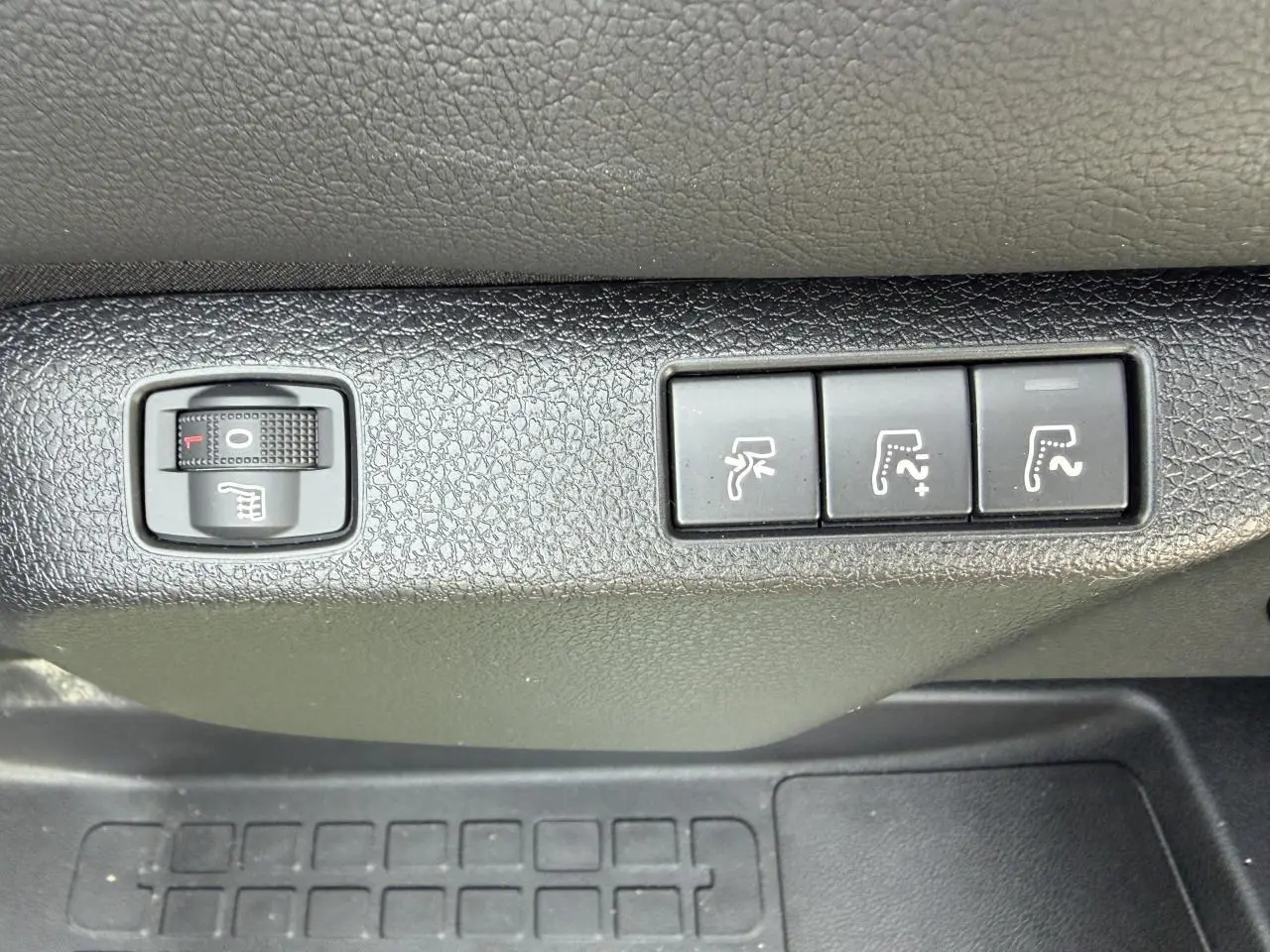Gros plan sur les commandes de réglage des sièges chauffants et électriques dans un Citroën Jumpy gris acier.