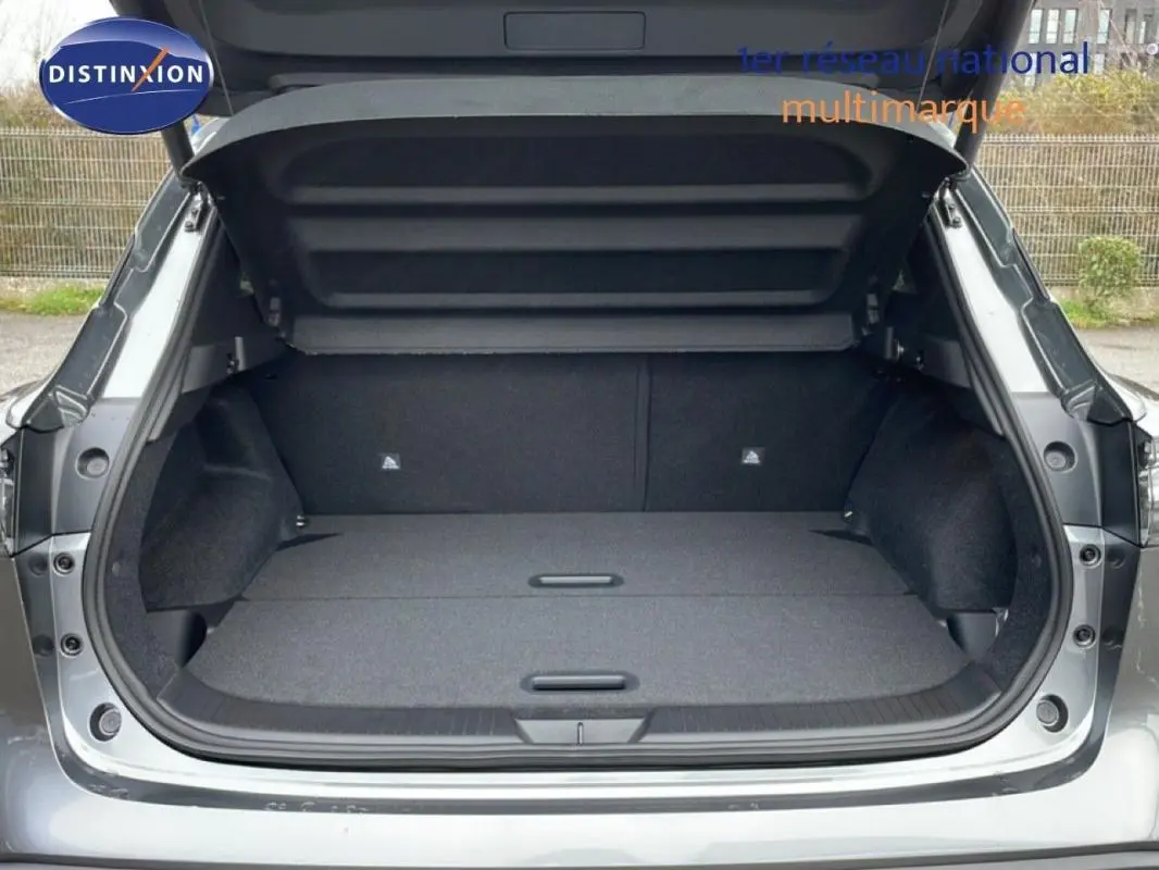 Coffre ouvert vu de l'arrière d'un Nissan Qashqai gris 2025, montrant un espace de chargement spacieux et propre.