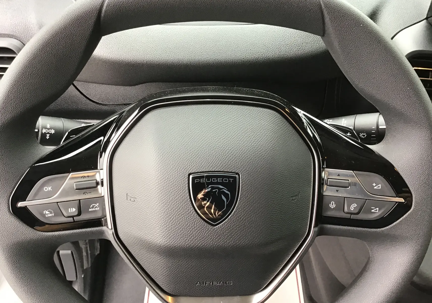 Vue rapprochée du volant noir du Peugeot Partner XL 2026 avec commandes intégrées et logo lion central.